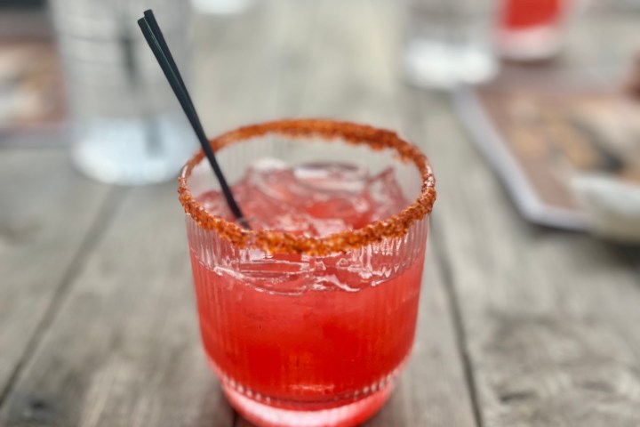 Red drink with a spice-rimmed glass on a wooden table.